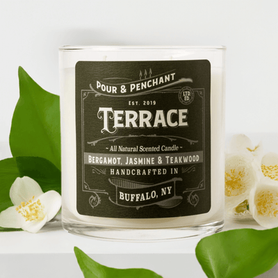 Pour & Penchant 10 oz Terrace Scented Candle surrounded by green ivy and white orchids and jasmine