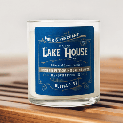 Pour & Penchant 10 oz Lake House Scented Candle on a teak wood bench with blurred gray background